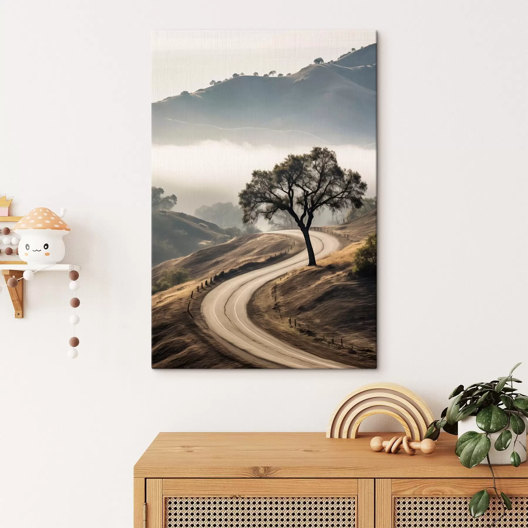 Fototapete Eine kurvenreiche Straße durch sanfte Hügel mit einem Baum im Vordergrund, im Hintergrund Nebel und Berge s46288